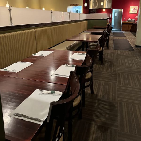 Empty dining room at Mintt Indian Cuisine with dark wood tables, chairs, and booth seating.