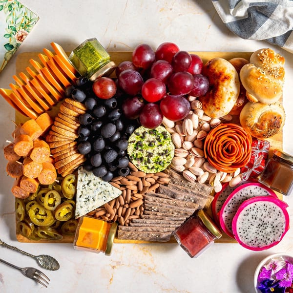 A charcuterie board filled with cheeses, meats, fruits, nuts, crackers, and various condiments.