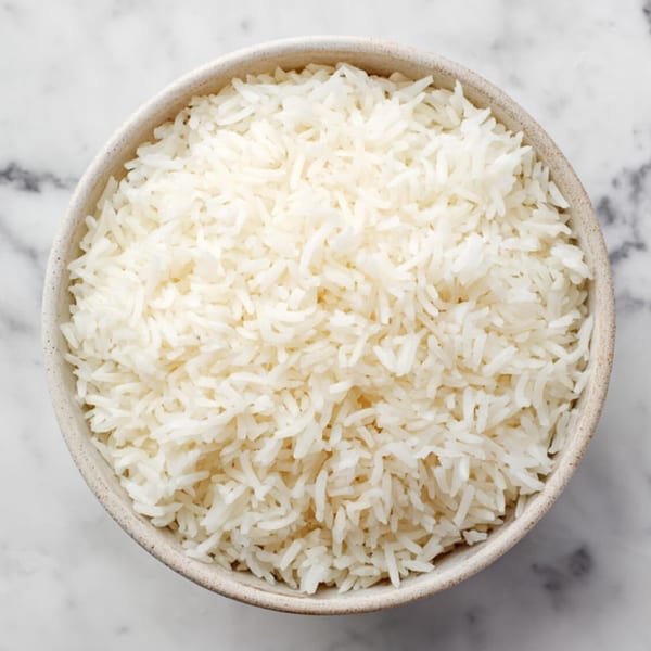 A white bowl filled with fluffy white rice, viewed from directly above on a marble surface.