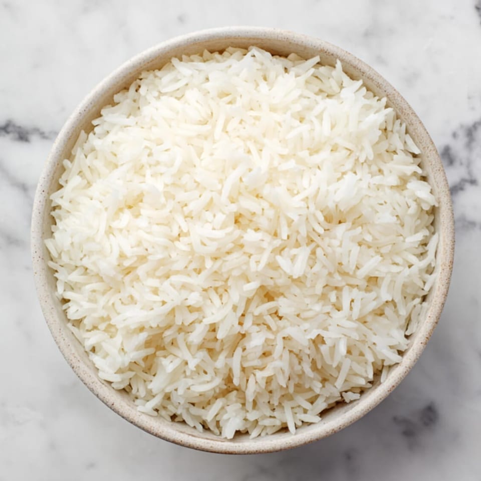 A white bowl filled with fluffy white rice, viewed from directly above on a marble surface.