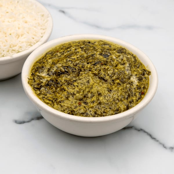 A bowl of vibrant green Indian palak paneer with a side of white rice.