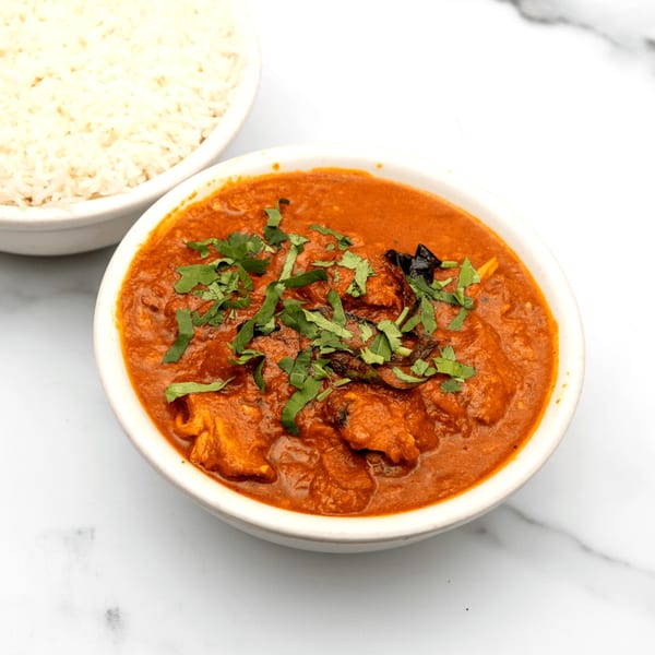 A bowl of Mintt Indian Cuisine's chicken tikka masala with cilantro, next to a bowl of white rice.