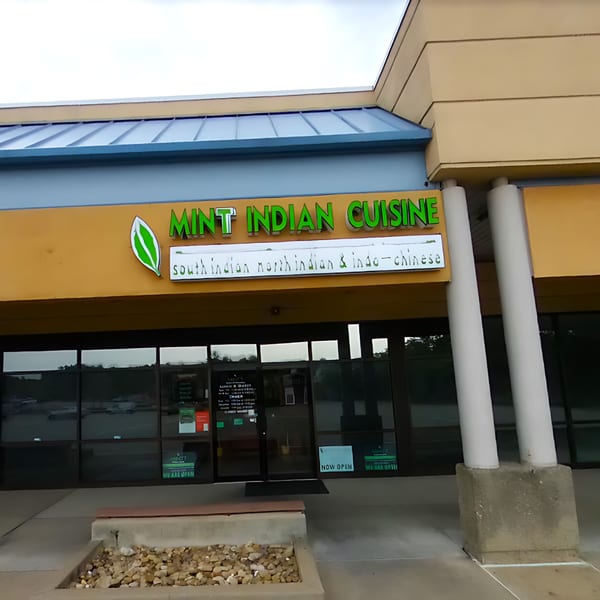 Exterior of Mintt Indian Cuisine, a restaurant with a green sign and large glass windows.