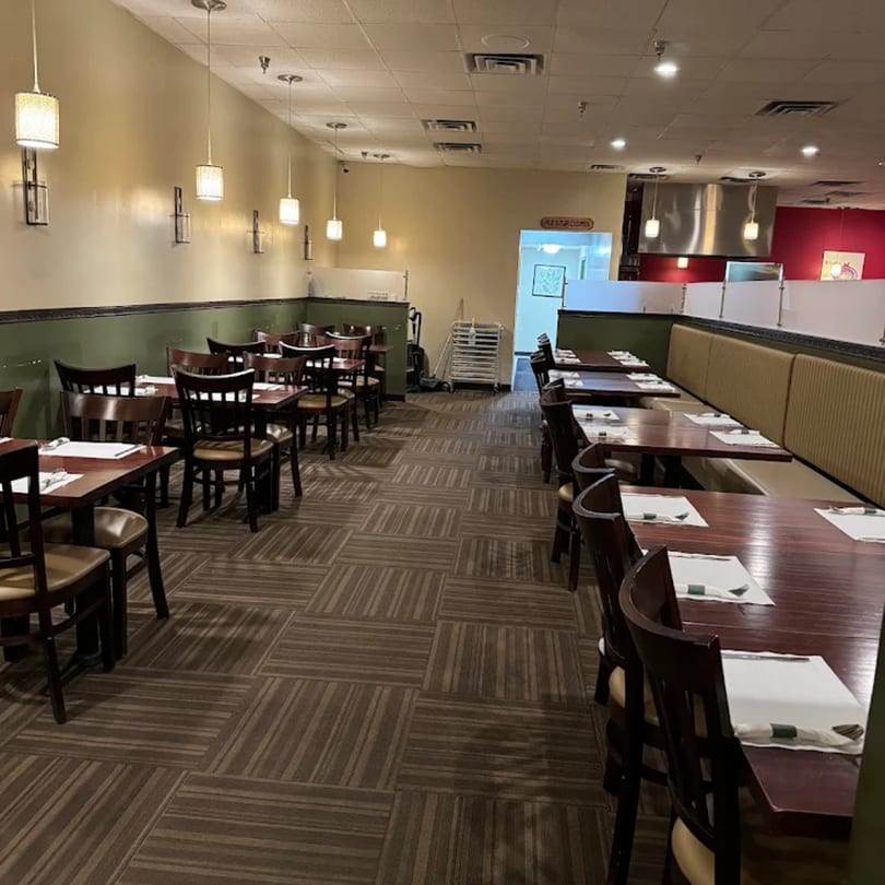Interior of Mintt Indian Cuisine restaurant with empty tables, chairs, and booth seating.