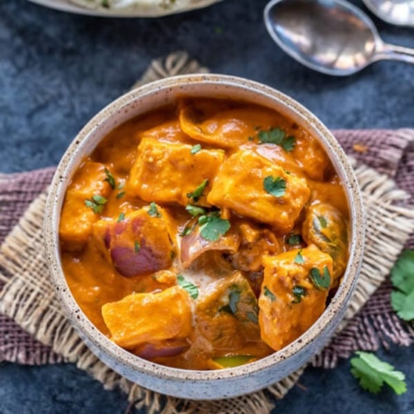 Close-up of a bowl of paneer tikka masala garnished with fresh cilantro.
