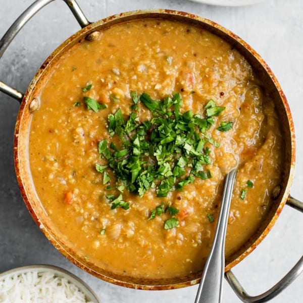 Overhead view of a copper pot filled with Indian dal, garnished with fresh cilantro.